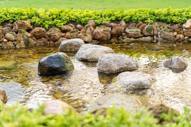 Pedra no pequeno rio fumegante criado por humanos no jardim no dia do sol