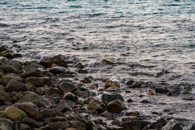 Pedra preta escura na praia no mar com pequenos caracóis toda aquela área É hora do crepúsculo na Tailândia asiática