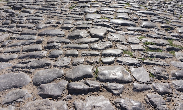 Pedras antigas irregulares em uma estrada pavimentada