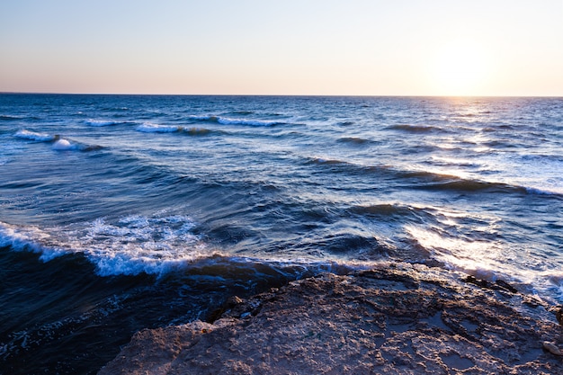 Pedras azuis bonitas do por do sol e da água sobre o Mar Negro