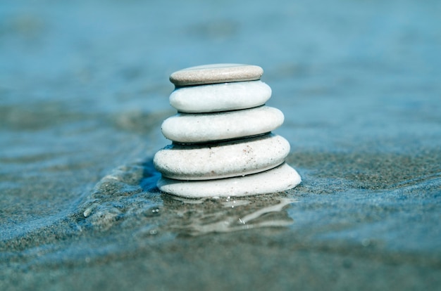 Pedras brancas de seixos de praia. Rochas equilibradas em águas do mar rasas para meditação de spa.