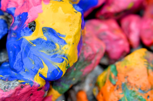 Pedras cobertas com close-up de tinta colorida. Pedras na pintura com listras. Fundo abstrato