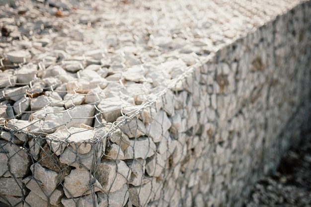 Pedras de granito atrás de uma grade de metal para fortalecer as pedras da encosta atrás da textura cinza de arame