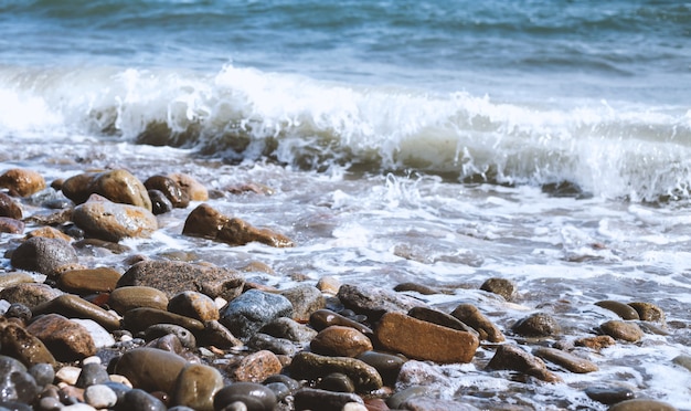 Pedras de seixo à beira-mar. Ondas do mar azul sedoso