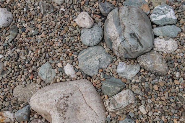 Pedras de seixo na margem do rio na natureza como pano de fundo