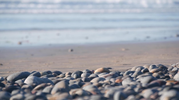 Pedras de seixo praia de areia oceano ondas de água do mar em volta de pedras lisas ou pedregulhos