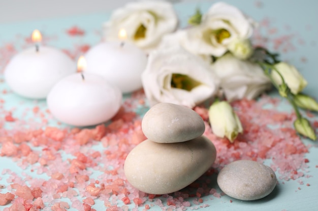 Pedras de spa com velas e flores em closeup de fundo azul