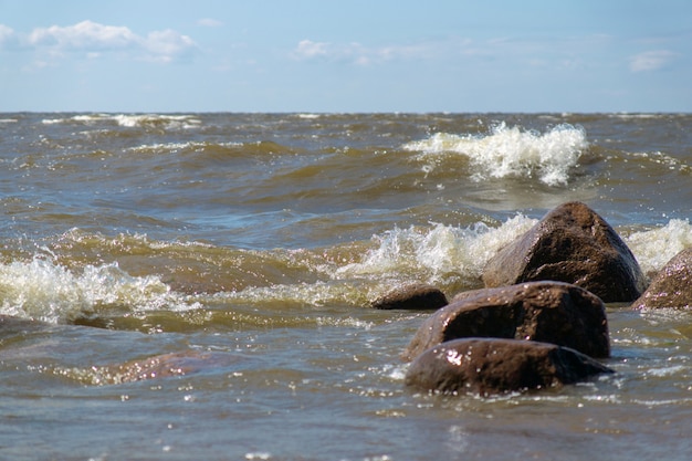 Pedras na praia do mar lavada pelas ondas em um dia ensolarado de verão
