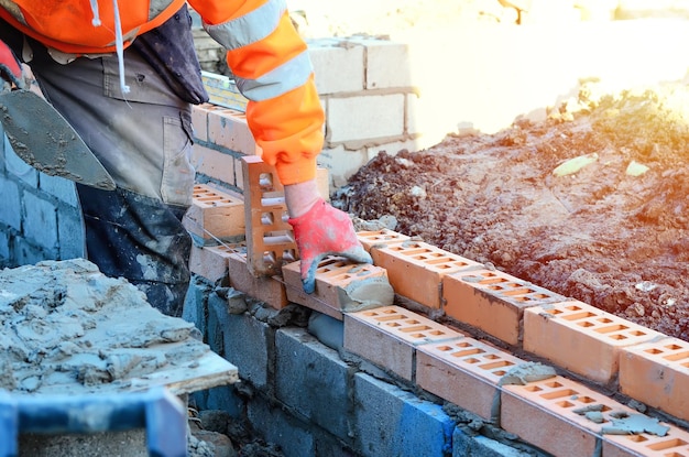 Pedreiro industrial colocando tijolos na mistura de cimento no canteiro de obras Lutando contra a crise imobiliária