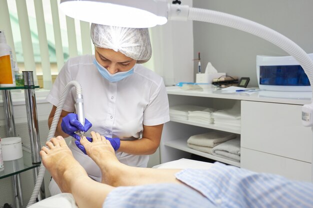 Peeling pies pedicura procedimiento SPA en el salón de belleza. Aparato eléctrico para pedicura. Mujer recibiendo sus pies pelados en el centro de spa