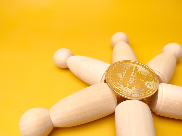 Peg doll y bitcoin sobre un fondo amarillo con espacio de copia