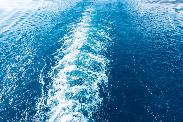 Pegada na água do navio Onda branca na água azul Água do mar azul Água e céu