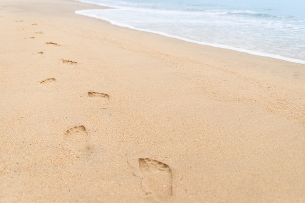 Pegadas andando na praia e ondas