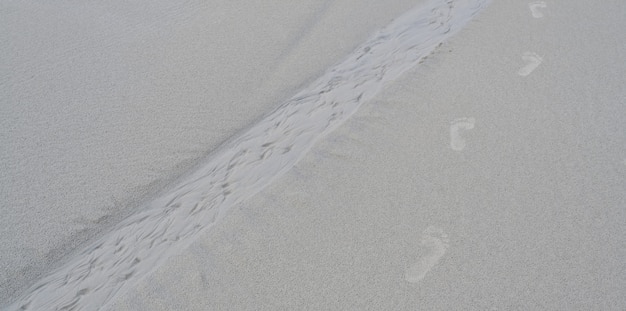 Pegadas de pés humanos na areia branca