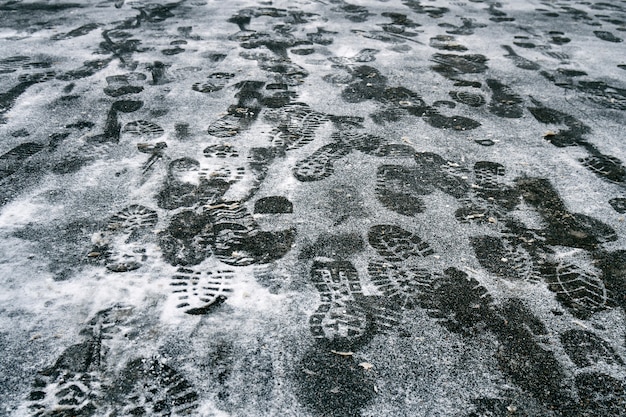 Pegadas de pessoas na neve no asfalto no inverno