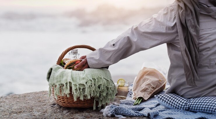 Foto pegando um lanche rápido na praia foto retrovisor de uma mulher idosa irreconhecível pegando um sanduíche de sua cesta de piquenique na praia