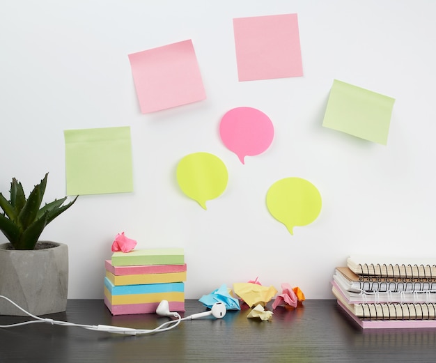 Foto pegatinas de colores pegadas a una pared blanca, sobre la mesa una pila de cuadernos