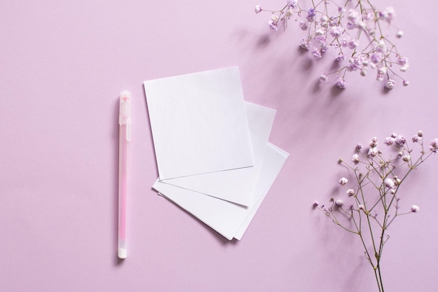 Pegatinas para escribir con un bolígrafo sobre un fondo morado junto a una cinta blanca y flores blancas