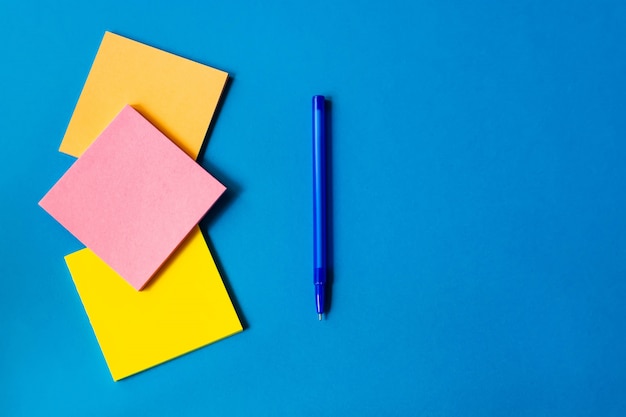 Pegatinas para notas y pluma se encuentran sobre un fondo azul.