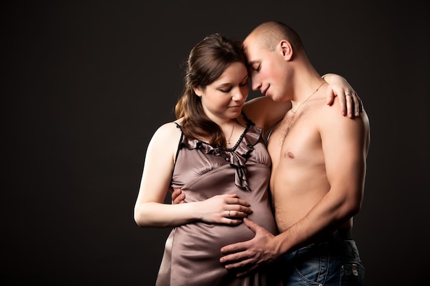 Pegnant mujer abrazando a hombre sin camisa