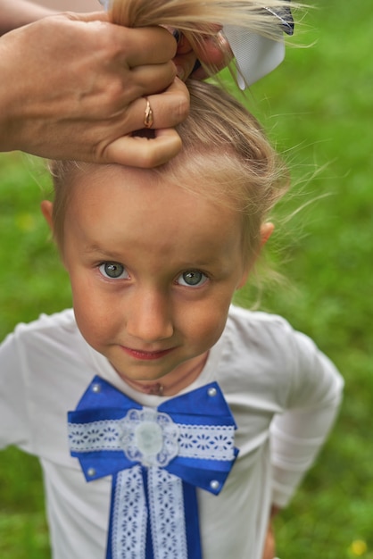 Se peina el cabello de una niña y se ata un lazo. Tiro vertical