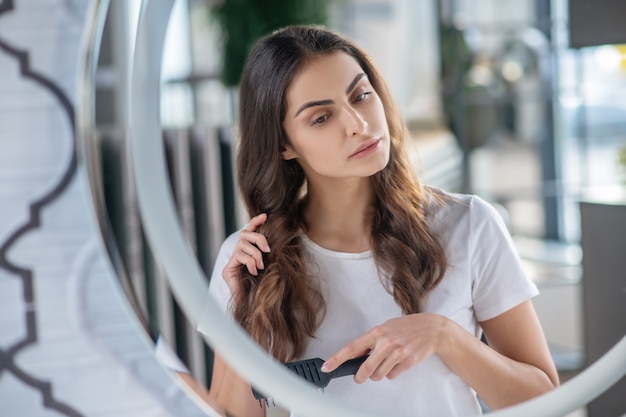 Peinado. Una mujer peinándose el pelo brillante por la mañana