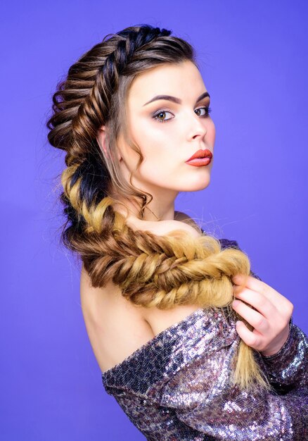 Peinado trenzado. Hermosa mujer joven con peinado moderno. Arte de peluquería de salón de belleza. Cara de maquillaje de niña trenzada pelo largo. Trenza francesa. Cuidado del cabello profesional y creación de peinado.