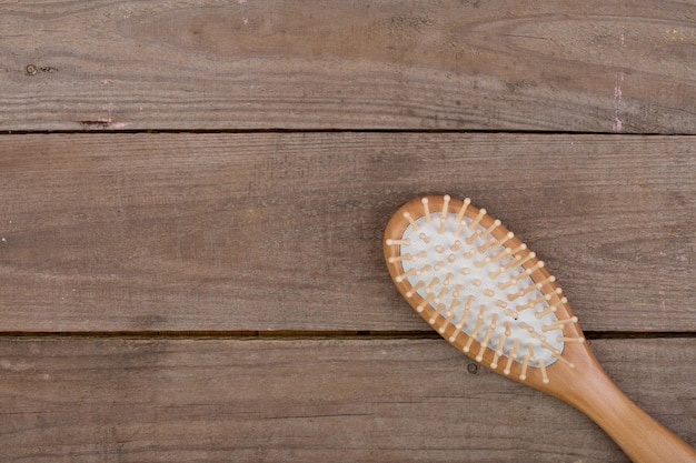 Peine cepillo de madera para el cabello sobre fondo de madera marrón