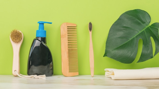 Un peine, jabón líquido, un cepillo de dientes y una toalla sobre un fondo verde. Accesorios masculinos para el cuidado de la apariencia.