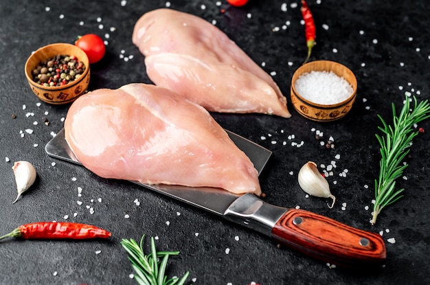 peito de frango cru com ingredientes na mesa de pedra