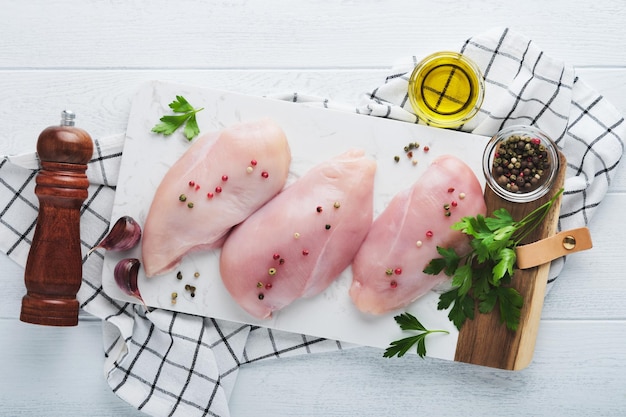 Peito de frango Dois filé de frango com especiarias azeite e salsa na tábua de pedra branca no fundo da mesa de madeira branca Vista superior com espaço de cópia Fundo de cozimento de carne de comida