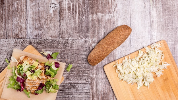 Peito de frango fresco grelhado na tábua de madeira e pão saudável ao lado