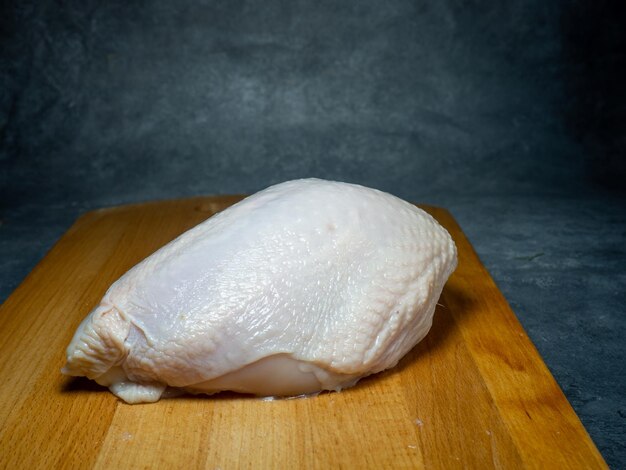 Peito de frango inteiro com pele em uma tábua Comida em fundo preto Carne crua