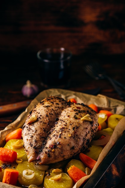 Foto peito de frango temperado assado no forno com legumes na assadeira