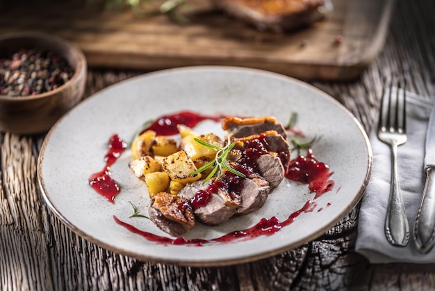 Peito de pato culinariamente preparado com batatas assadas e molho de cranberry