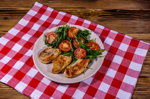 Peitos de frango assado e salada com rúcula e tomate cereja em um prato de cerâmica