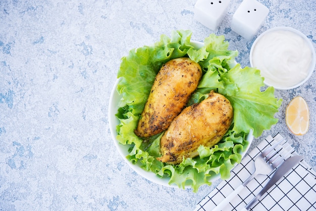 Peitos de frango assados em especiarias e óleo com ervas frescas para o jantar, comida saudável em um fundo claro, foco seletivo, espaço de cópia