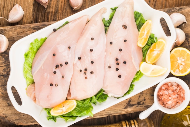 Peitos de frango crus e temperos na tábua de madeira,