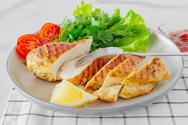 Peitos de frango grelhados servidos em um prato com salada e legumes. Alimentos dietéticos.