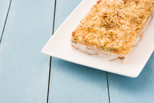 Peixe branco com queijo na mesa de madeira azul