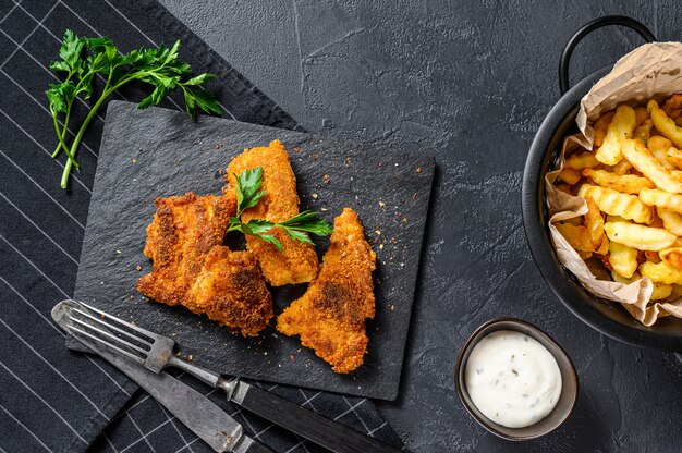 Peixe com batatas fritas, batata frita e filé de bacalhau frito na farinha de rosca. Vista do topo