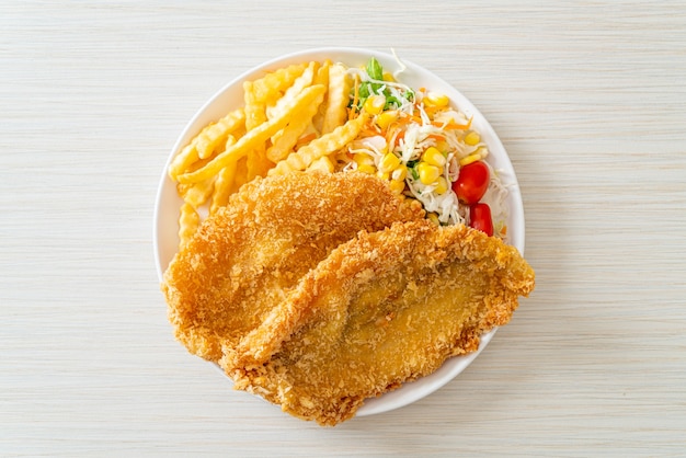 Foto peixe com batatas fritas com mini salada no prato branco