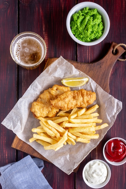 Peixe com batatas fritas em um de madeira. Fast-food britânico. Receitas. Lanche de cerveja. Cozinha inglesa.