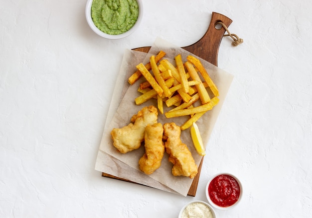 Peixe com batatas fritas em uma superfície branca. fast food britânico. receitas lanche para cerveja. comida tradicional britânica.