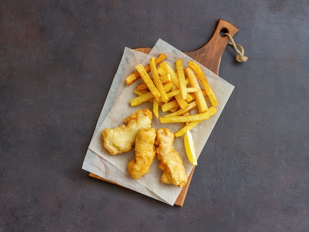 Peixe com batatas fritas em uma superfície escura. fast food britânico. receitas lanche para cerveja. comida tradicional britânica.