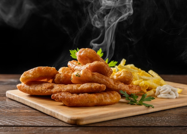 Foto peixe com batatas fritas na tábua de cortar com vapor