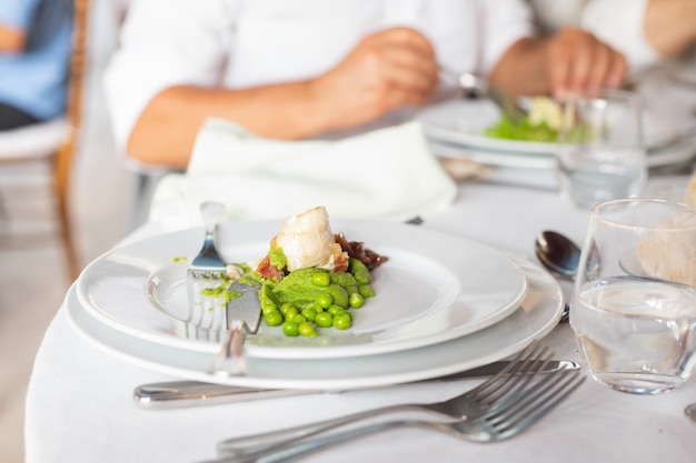 Peixe com ervilhas na chapa branca em restaurante