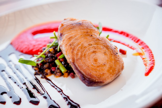 Peixe com legumes em um prato branco. Restaurante.