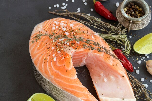 Peixe cru de bife de salmão preparado para cozinhar. Vista superior na mesa preta.