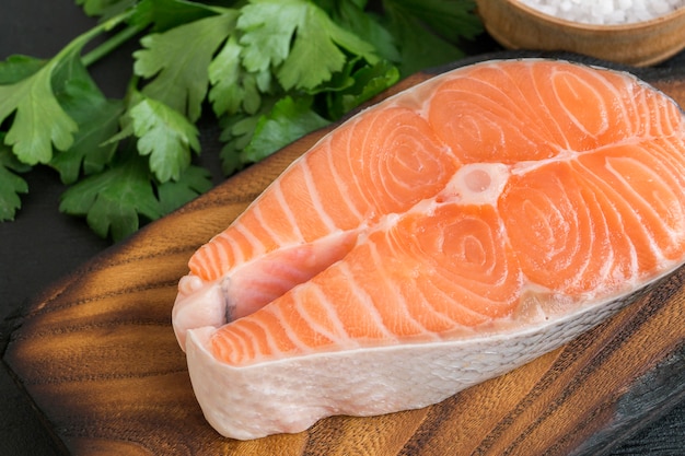 Peixe cru de bife de salmão preparado para cozinhar. Vista superior na mesa preta.